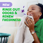 Smiling person holding a towel with text saying rinse out odors & renew freshness and small Gain floral accents