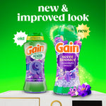 Promotional graphic showing old and new Gain scent booster Moonlight Breeze packaging on a bright green background.