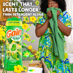 Person inhaling a green garment beside a large Gain scent booster graphic with flowers and claim 'Scent that lasts longer than detergent alone'.