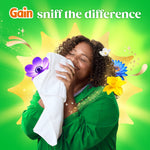 Smiling woman inhaling a white towel against a green background with Gain branding and floral graphics