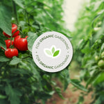 Close-up image of ripe red tomatoes and blurred foliage with a circular 'For Organic Gardening' badge overlaid on the scene.