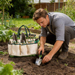 Gardener kneeling in a vegetable bed using a stainless steel trowel with a canvas tool bag and hand tools beside him