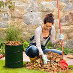 Person raking leaves next to a dark green collapsible garden pop-up waste container filled with leaves