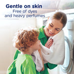 Woman and child hugging a white towel near a washing machine with copy stating gentle on skin, free of dyes and heavy perfumes