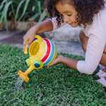 Child outdoors pouring water from a yellow striped bug watering can with a flower spout onto grass