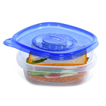 Clear Glad square food container with blue lid partially closed over a sandwich inside