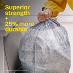Hand holding a tied patterned Glad ForceFlex trash bag beside a counter with text 'Superior strength + 25% more durable'