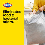 Lifestyle image showing a person tying a patterned Glad trash bag next to bold yellow panel reading “Eliminates food & bacterial odors.”