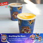 Two Glad Paw Patrol paper cups on a table, one filled with orange liquid and one with coffee in background
