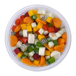 Top-down view into a clear Glad bowl filled with colorful cubed and sliced fruit visible through the rim.