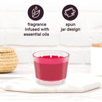 Pink three-wick Glade candle on a surface with icons and text calling out fragrance infused with essential oils and spun jar design