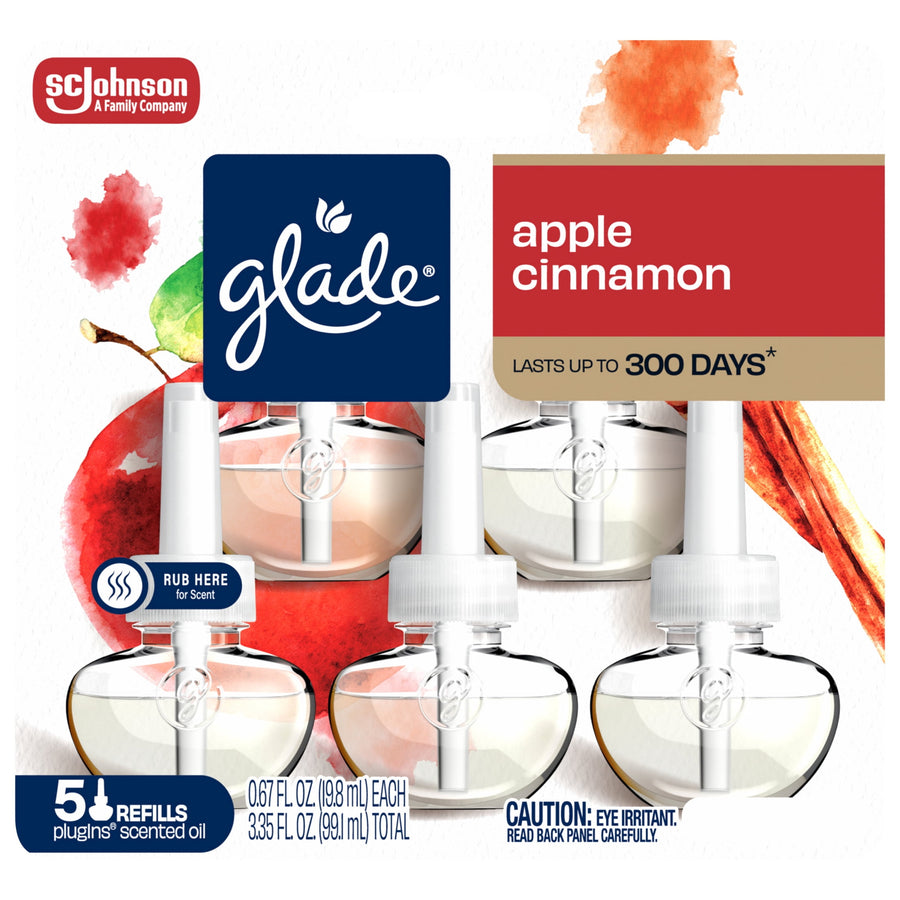 Front packaging close-up of Glade Apple Cinnamon plug-ins showing logo, apples, cinnamon stick, and refill bottles