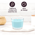 Styled product image of a lit aqua-blue three-wick candle on a white surface with icons reading 'fragrance infused with essential oils' and 'spun jar design'
