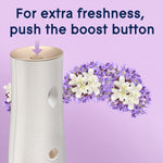 Close-up of Glade automatic dispenser top with an arrow indicating the boost button and floral accents