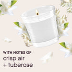 Illustrated lit white candle in a clear jar surrounded by white flowers with text noting notes of crisp air and tuberose