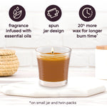 Glade Cashmere Woods lit candle on a surface with icons noting essential oils, spun jar design, and more wax