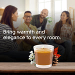 Lifestyle image with a lit Glade Cashmere Woods candle on a table and blurred group of people in the background with headline about warmth