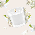 Close-up illustration of a lit clear glass jar candle with white floral accents on a pale background