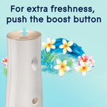 Close-up of Glade dispenser top with arrow pointing to boost button and floral wave artwork in background