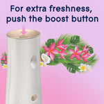 Top-view of Glade dispenser showing boost button with arrow and decorative tropical flowers behind it