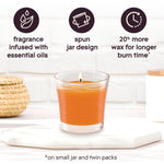 Single lit orange Glade candle in a textured glass jar with icons highlighting fragrance features