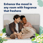 Lifestyle image of a smiling couple on a couch with copy encouraging enhancing the mood in any room with fragrance that freshens.