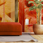 Close lifestyle interior showing a wall-mounted Glade PlugIns warmer beside a red ottoman and large potted plant against a tropical patterned wall