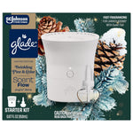 Packaged Glade Scent Flow starter kit featuring the device and refill against a festive pinecone and frosted evergreen background.