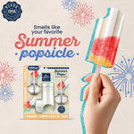 Hand holding a multicolored popsicle next to Glade Summer Pops PlugIns starter kit on a decorative fireworks background