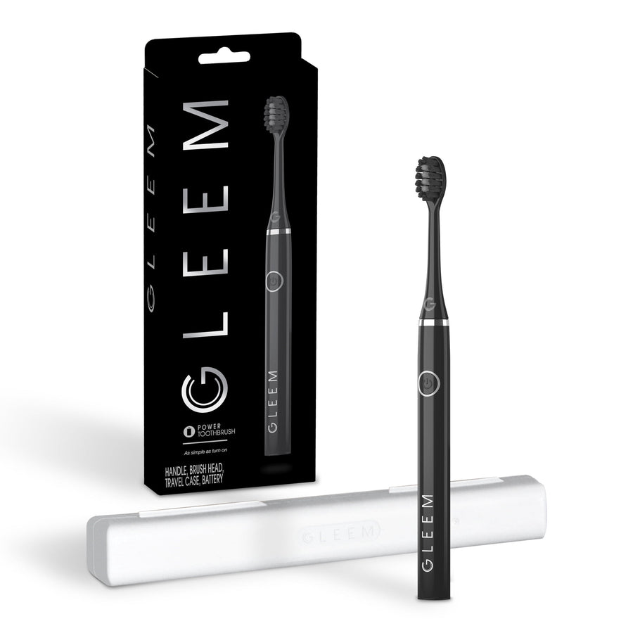 Black Gleem battery-powered toothbrush upright with white travel case and retail box on white background.