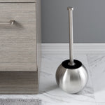 Globe-shaped stainless steel toilet brush holder placed on bathroom floor with brush inserted