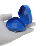 Hand wearing white glove holding an open glossy blue triangular plastic case for braces or retainers.