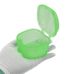 Open translucent green plastic braces or retainer case held in a gloved hand against white background