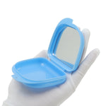 Hand wearing white glove holding open blue retainer case showing interior mirror and shallow storage well