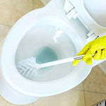 Gloved hand holding a toilet brush scrubbing a white bowl with pale blue cleaning solution visible in the water.