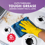 Close-up of a gloved hand wiping a greasy stovetop area with a blue cloth next to a 0% bleach badge