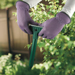 Close-up of gloved hands holding a green solar-powered sonic spike device for lawn pest repelling