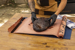 Gloved hands lifting a smoked brisket from Pit Boss branded butcher paper on a table