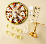 Styled overhead tabletop scene with gold mini forks, dessert platter, cups and a small gold cake stand