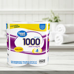 Lifestyle-style photo of a four-roll Great Value 1000 bath tissue pack on a white wood surface with blurred towels in background