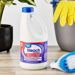 Great Value bleach bottle placed on a tabletop with cleaning brush, plant, and rubber gloves in the scene.