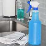 Blue-tinted spray bottle with a white and blue trigger sitting on a kitchen counter near a sink and folded towel.