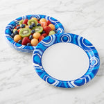 Stack of blue swirl Great Value paper plates on a marble surface, one plate filled with fruit salad.