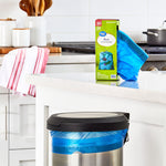 Kitchen scene with a Great Value box of blue drawstring bags on a counter and a blue bag lining a stainless trash can