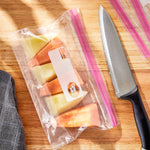 Clear resealable storage bag on a cutting board holding melon slices with a chef's knife nearby