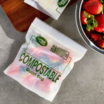 Close-up overhead of a Great Value compostable quart bag filled with colorful contents next to a bowl of strawberries