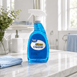 Great Value glass cleaner bottle with blue liquid and white trigger staged on a marble bathroom counter with a towel and sink in background.