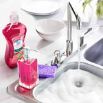 Kitchen sink scene with a bottle of pink Great Value guava dish soap, a pump dispenser, sponge and soapy running water.