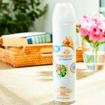 Great Value Hawaiian aerosol air freshener can displayed upright on a table with blurred wicker tray and pink flowers in background.