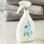 White spray bottle of Great Value Linen Fresh odor eliminator pictured on a countertop with folded towels in background